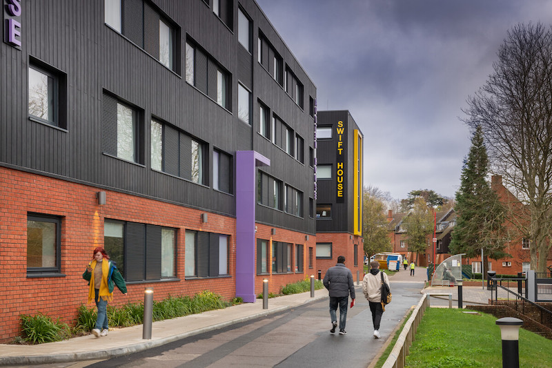 Image shows students walking alongside the new University Walk halls at UCA Farnham